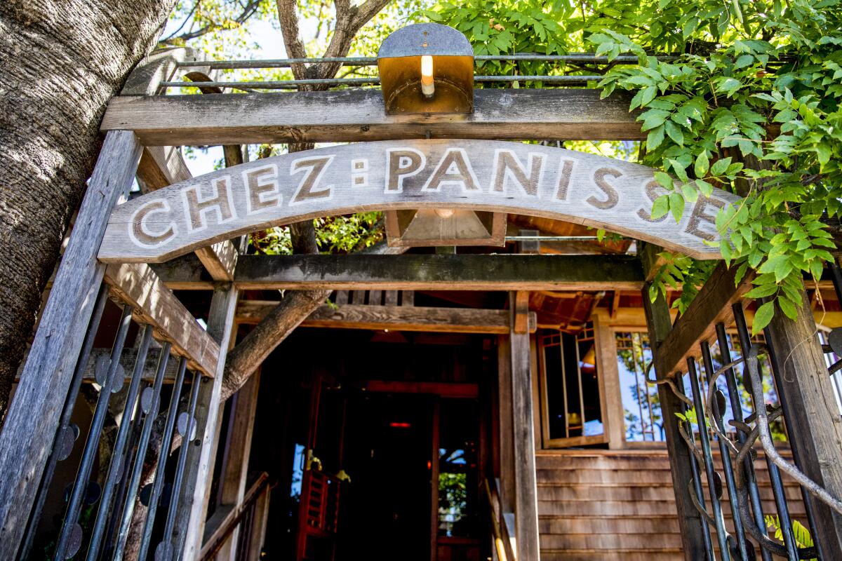 A sign reading "Chez Panisse" arches over a doorway into a wooden building.