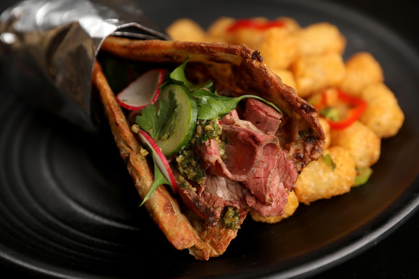 Chinese spiced pastrami, hazelnut pesto, Beijing mustard vinaigrette, served with salt and pepper tater tots at Ms. Chi restaurant in Culver City.