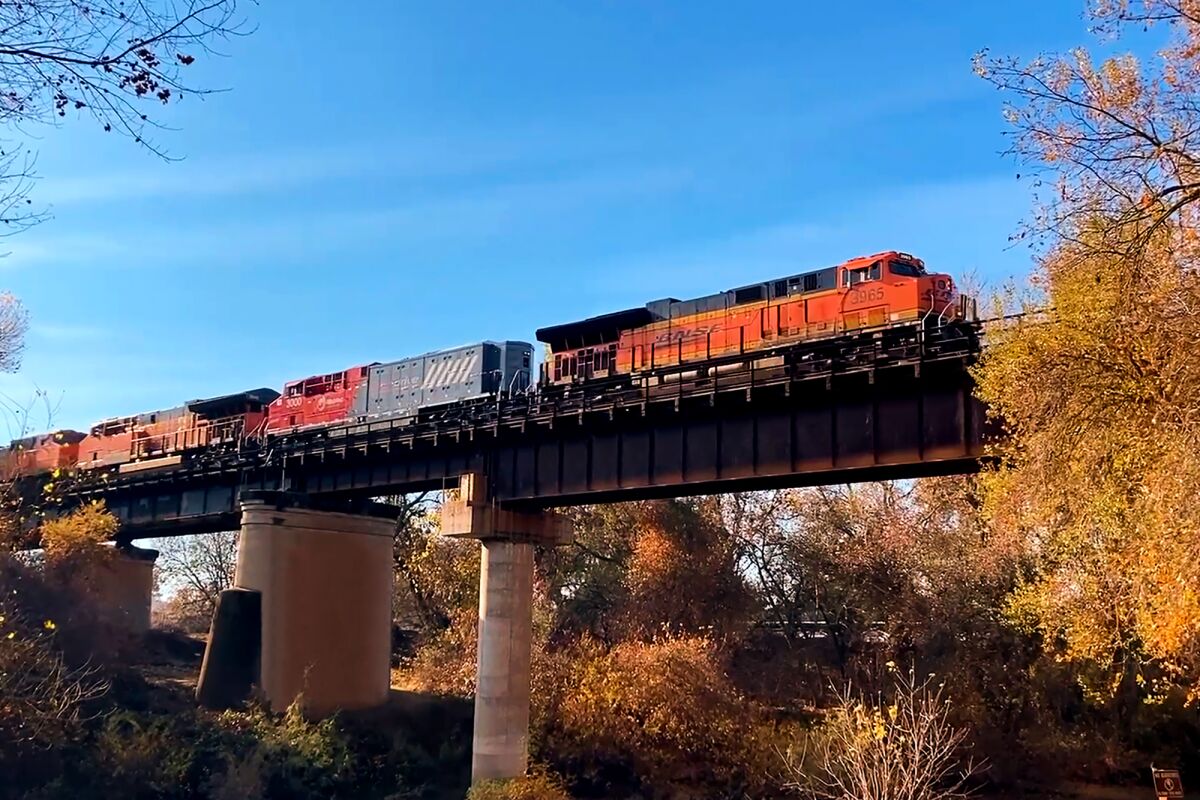 A battery-powered locomotive helps pull a BNSF train on a raised track