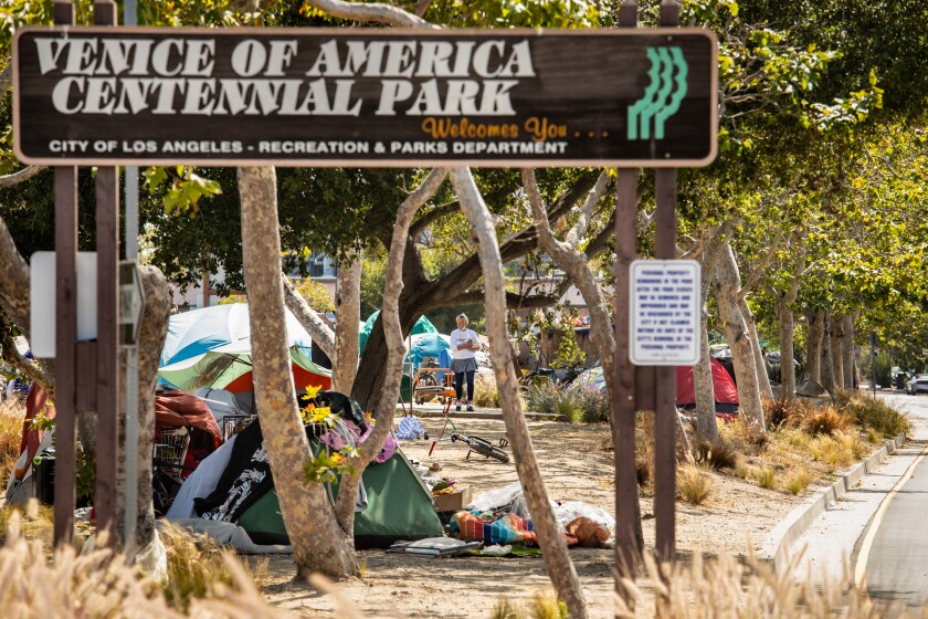 The sign for Centennial Park with a cluster of homeless tents