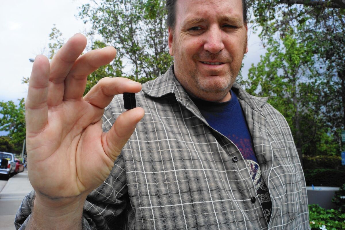 Ken Boland of Lake Forest holds a nano-geocache, an object in a worldwide scavenger hunting game known as Geocaching. It contains a small rolled up piece of paper that players of the game can sign once they're found the nano-cache.