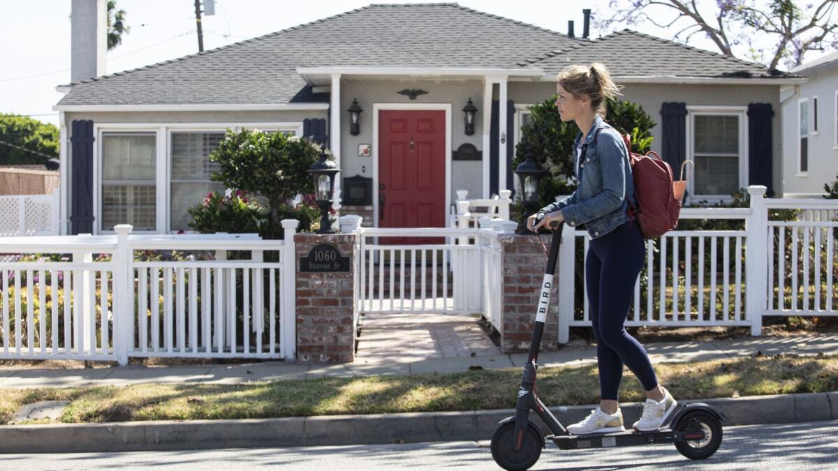 A woman rides a scooter down Stanford Street in Santa Monica where several homes were inherited.