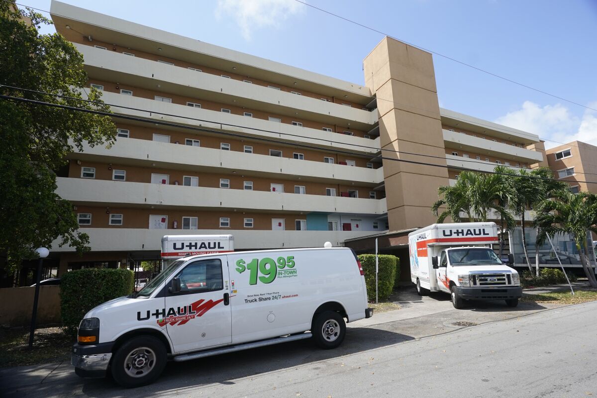 Moving vans and trucks are shown parked outside the Bayview 60 Homes apartment building, Tuesday, April 5, 2022, in North Miami Beach, Fla. City officials in North Miami Beach ordered residents of the five-story apartment building to evacuate after deeming the building "structurally unsound" during its 50-year recertification process. (AP Photo/Wilfredo Lee)