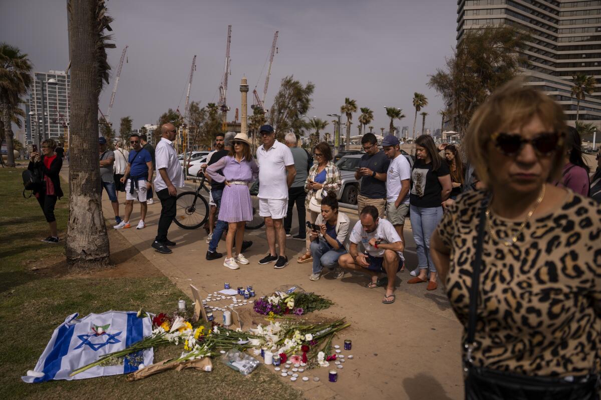 People gather and lay flowers at the outdoor path where Alessandro Parini was killed in a Palestinian attack.