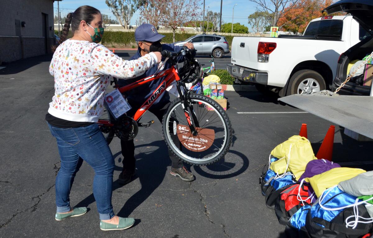 Gina Nunes and Adolfo Andrade, load a donated bike from Bicycle Santas into a truck to be distributed.