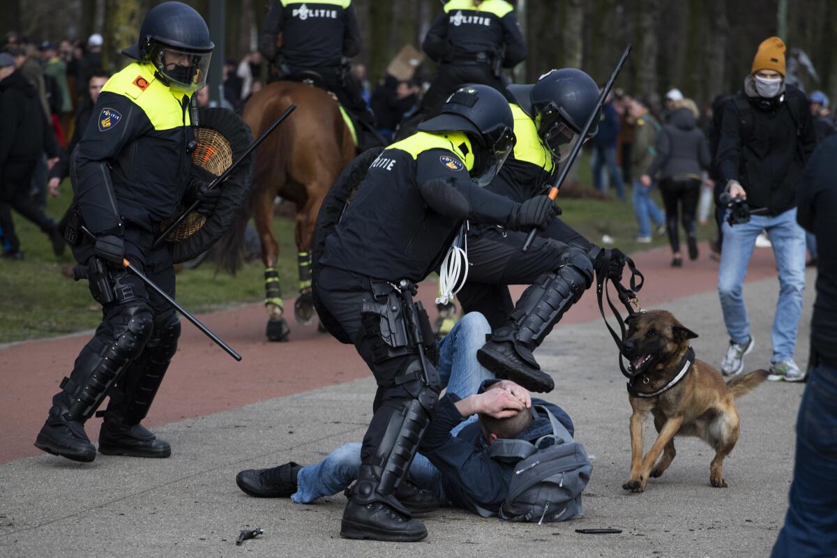 Dutch riot police kick a man during a demonstration to protest government policies including the curfew, lockdown and coronavirus related restrictions in The Hague, Netherlands, Sunday, March 14, 2021. Thousands of people took part in the rally ahead of three days of voting starting Monday in a general election. (AP Photo/Peter Dejong)