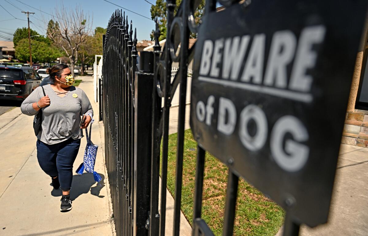  A woman walking on a sidewalk near the front gate of a home