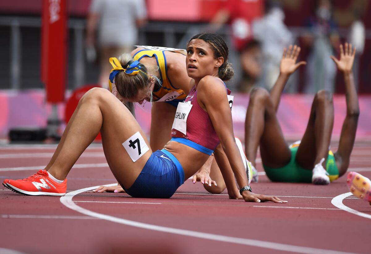 Sydney McLaughlin and other runners rest on the track after racing at the Tokyo Olympics.