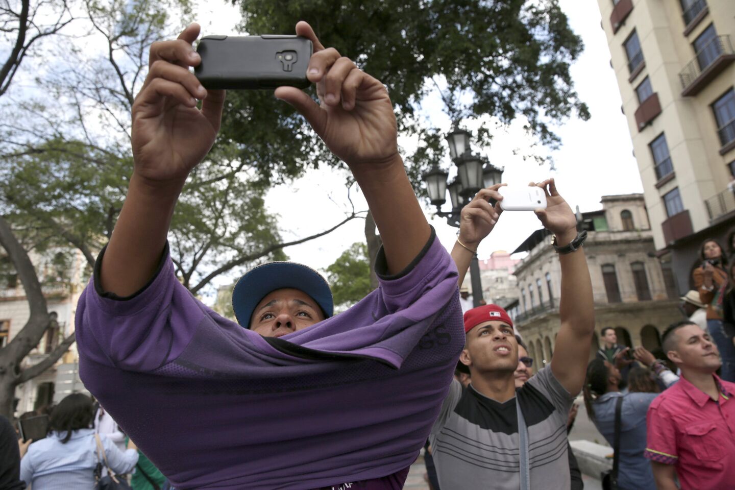Onlookers crane to shoot smartphone images of President Obama, who is stationed more than a block away at the El Gran Teatro de Havana in Central Havana.