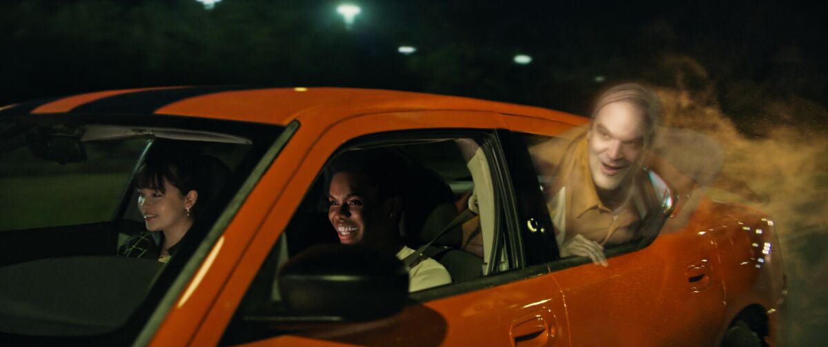 A ghostly figure hangs its head out a car window, dog-like.