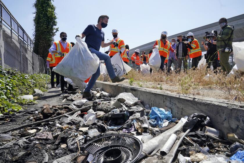 California Gov. Gavin Newsom, center, joins a cleanup effort Tuesday, May 11, 2021, in Los Angeles. Newsom on Tuesday proposed $12 billion in new funding to get more people experiencing homelessness in the state into housing and to "functionally end family homelessness" within five years. (AP Photo/Marcio Jose Sanchez)