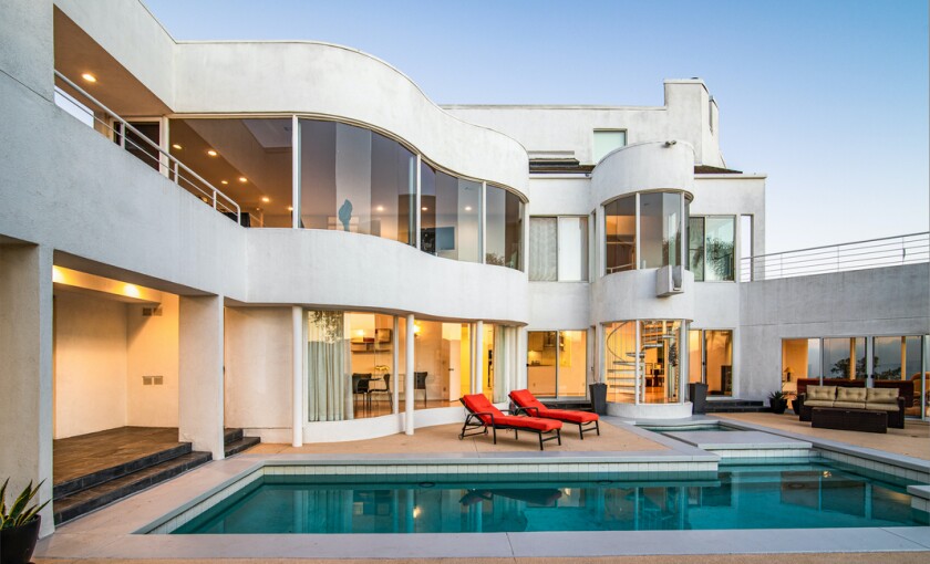 The modern home draws the eye with curving lines and a sleek whitewashed exterior.