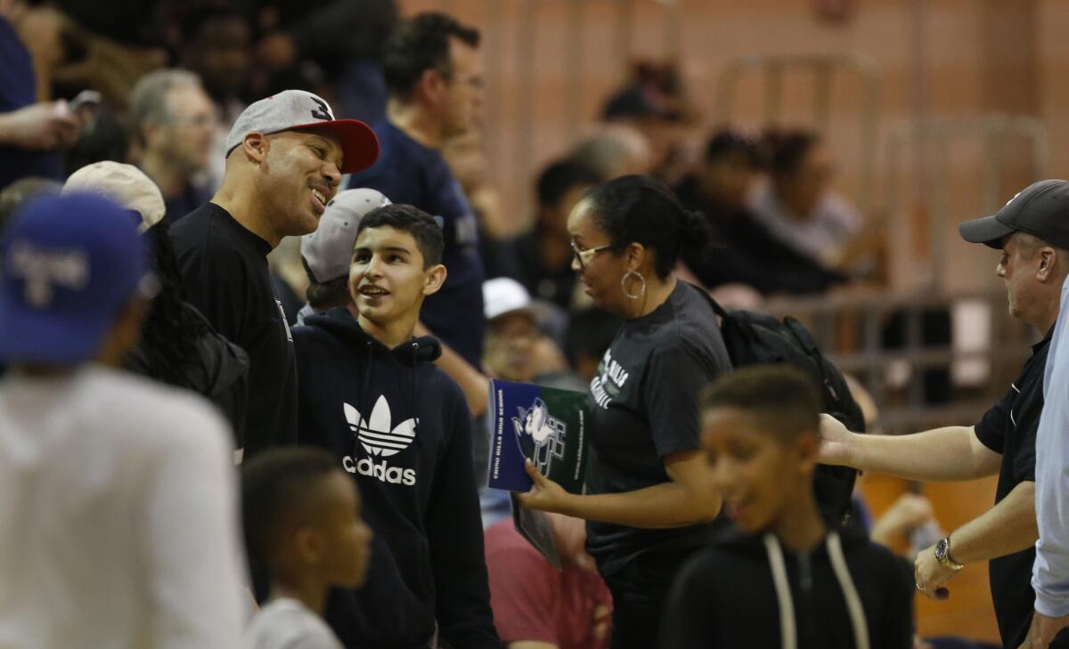 LaVar Ball, left, poses for photos with fans while watching son LaMelo Ball play for Chino Hills during a recent game at Rancho Cucamonga.