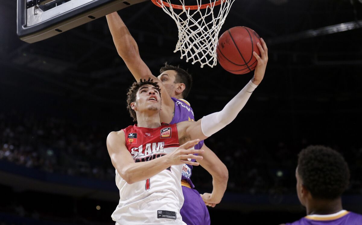 LaMelo Ball of the Illawarra Hawks, left, lays up around Andrew Bogut of the Sydney Kings.