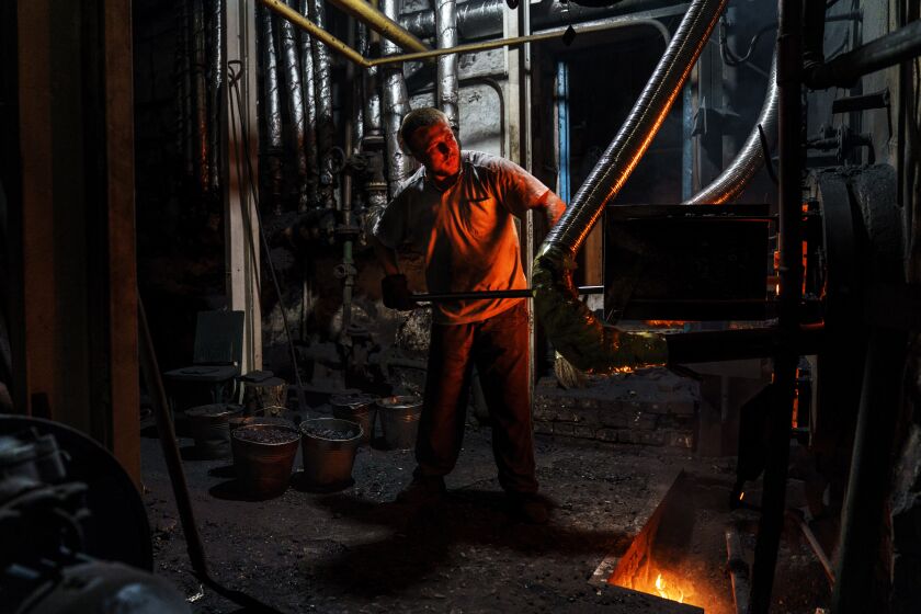 Dmytro, one of three men working a 12-hour night shift, loads coal into a boiler at a bakery in Kostiantynivka, Donetsk region, eastern Ukraine, Monday, Aug. 15, 2022. The bakery has remained open despite many challenges. In April it lost its gas supply, but the ovens were reconfigured to run on coal, a system which hadn't been used at this plant since World War II. It's one of two large-scale bakeries left in operation in the Ukrainian-held part of the Donetsk region, most of which is under Russian occupation. (AP Photo/David Goldman)