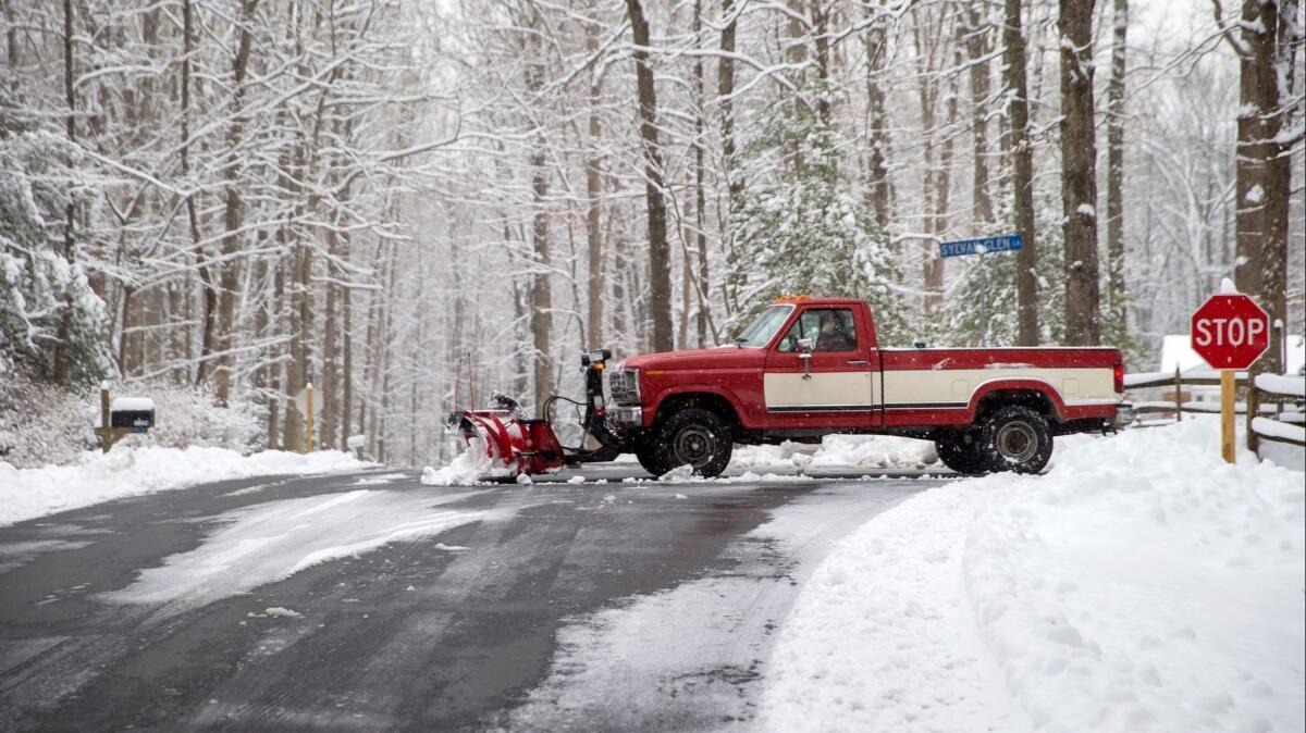 A snowplow operator clears a private road Sunday after a winter storm dumped a blanket of snow in Fairfax Station, Va.