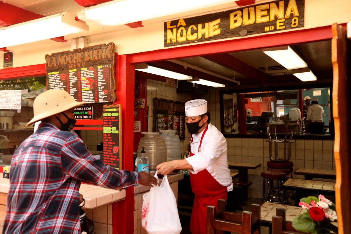 Baltazar Ayala, a cook at La Noche Buena, served a takeout meal to a customer on Wednesday.