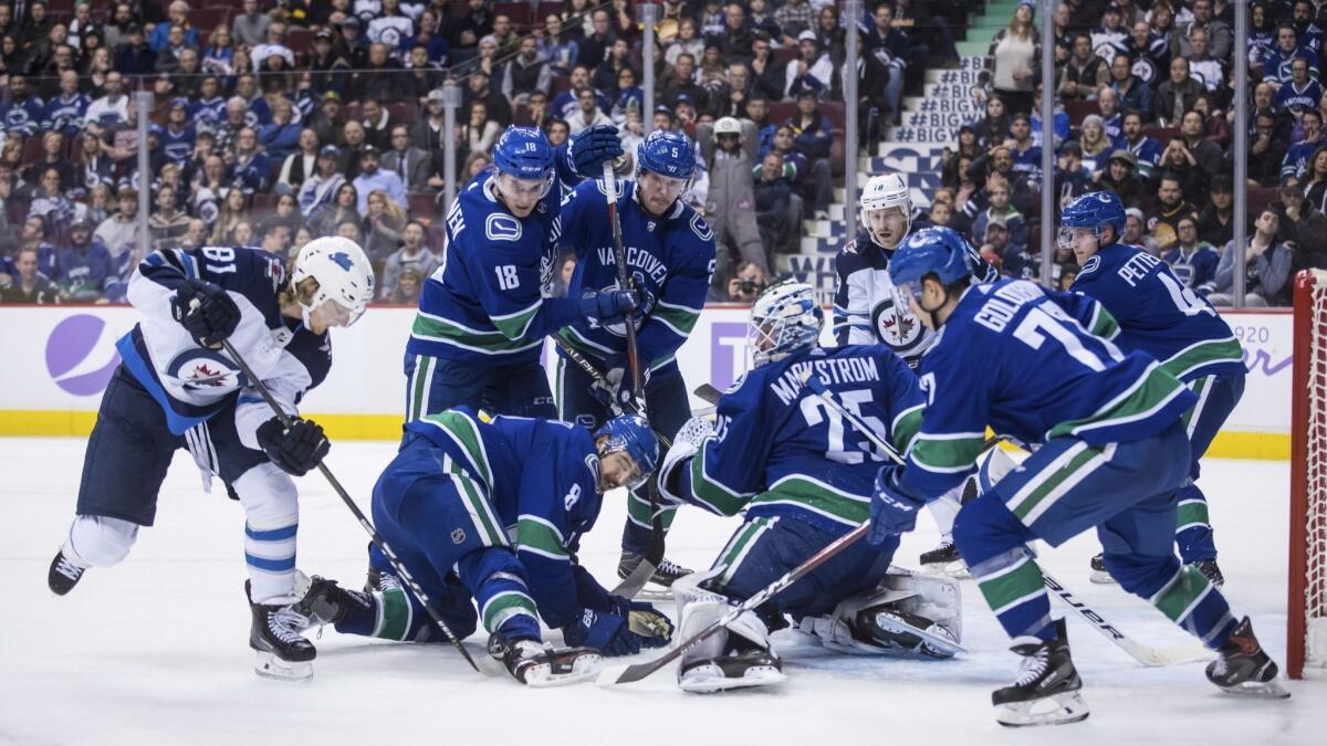 Winnipeg Jets and Vancouver Canucks players battle for the puck during the game on Tuesday.