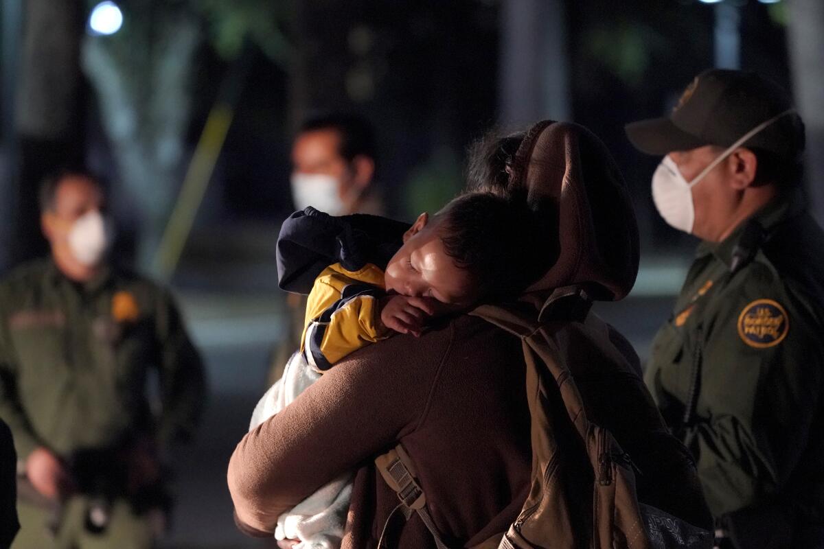 Una migrante con su bebé dormido llega a un centro de detención recepción del servicio de inmigración