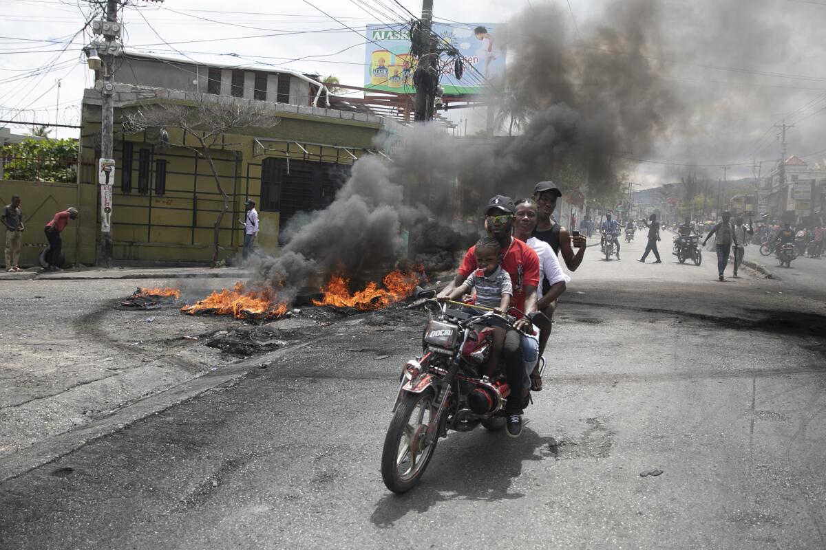 Un taxista en motocicleta traslada a clientes cerca de una protesta contra la creciente violencia