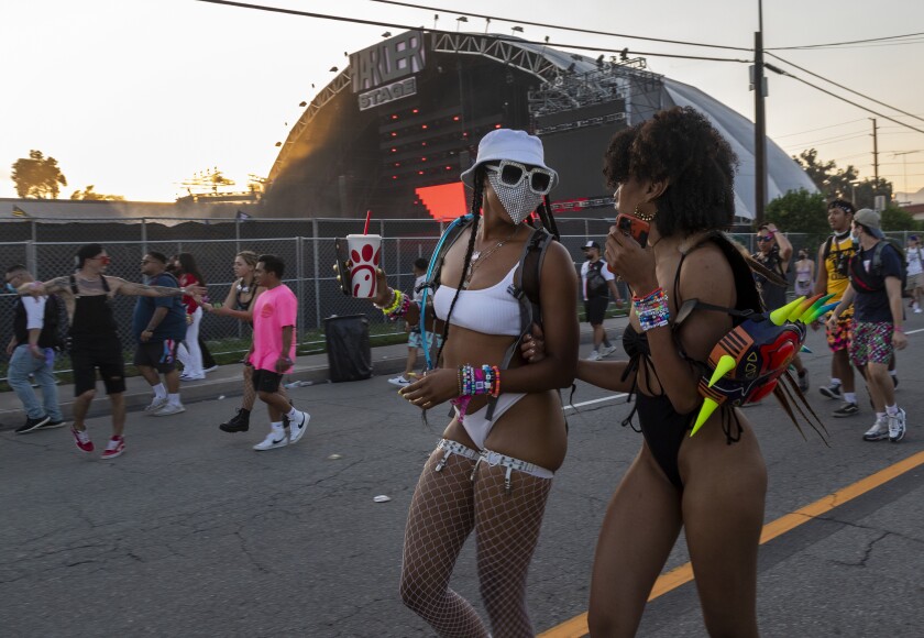 A masked and an unmasked fan walk in front of other groups of people