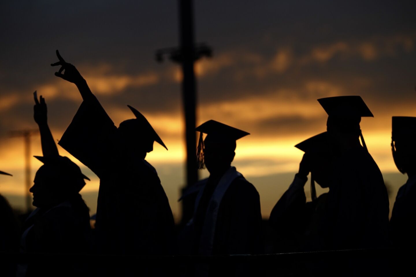Santa Monica College graduates are silhouetted at sunset as they line up to receive their diplomas during a graduation ceremony that also served as a memorial at Corsair Field.