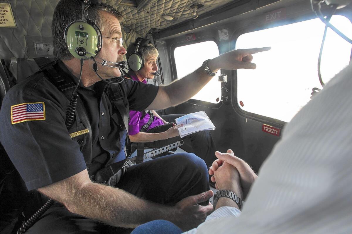 U.S. Secretary of the Interior Sally Jewell, rear, San Diego Asst. Fire Chief Brian Fennessey, left, and Rep. Scott Peters (D-San Diego), not visible at right, tour by helicopter parts of San Diego County burned by the massive Cedar fire in 2003.