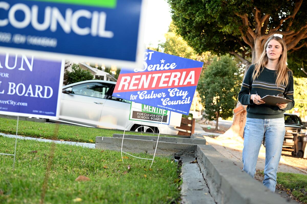 A teen walks in a neighborhood by political yard signs