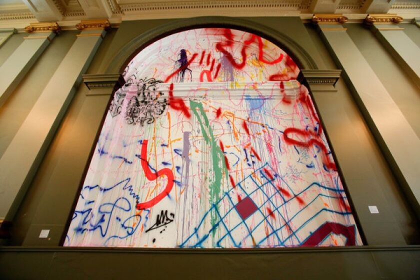 Runaway, 2013, by Sarah Cain, an acrylic, vinyl and string on window and wall, is on display at Painting in Place sited in the Farmers and Merchants Bank on Main St. in Downtown Los Angeles.