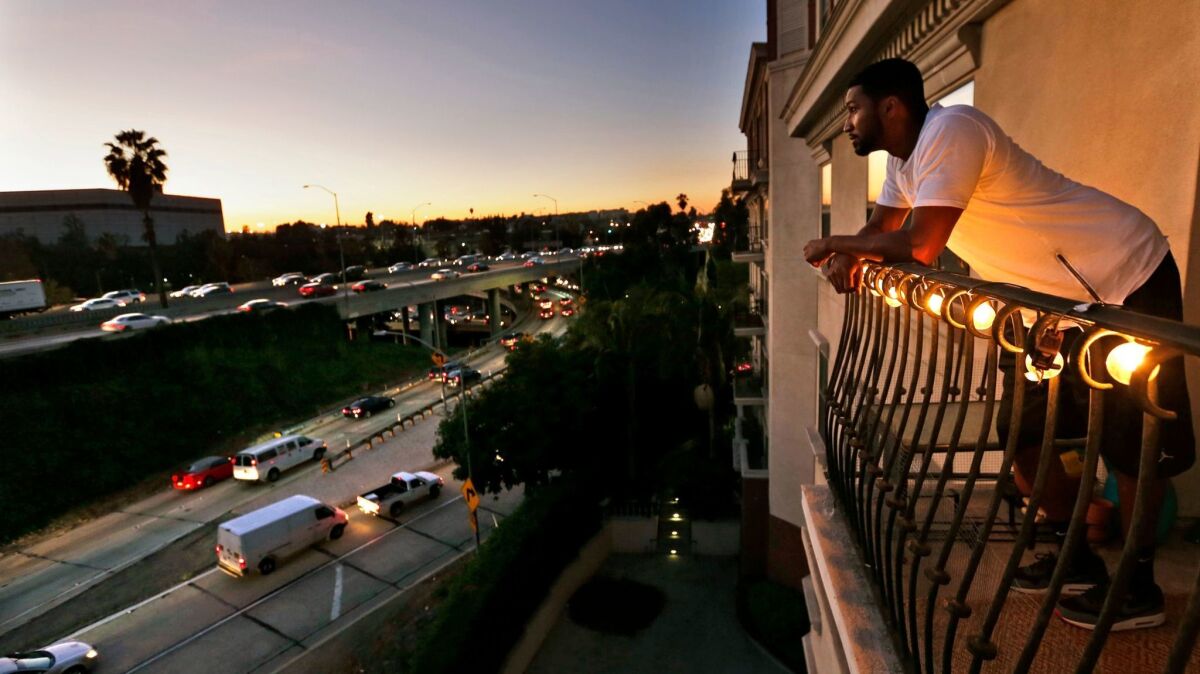 Everett Smith looks out at rush-hour traffic on the 101-110 freeway interchange from his seventh-floor balcony at the Orsini apartments in downtown Los Angeles in 2015.