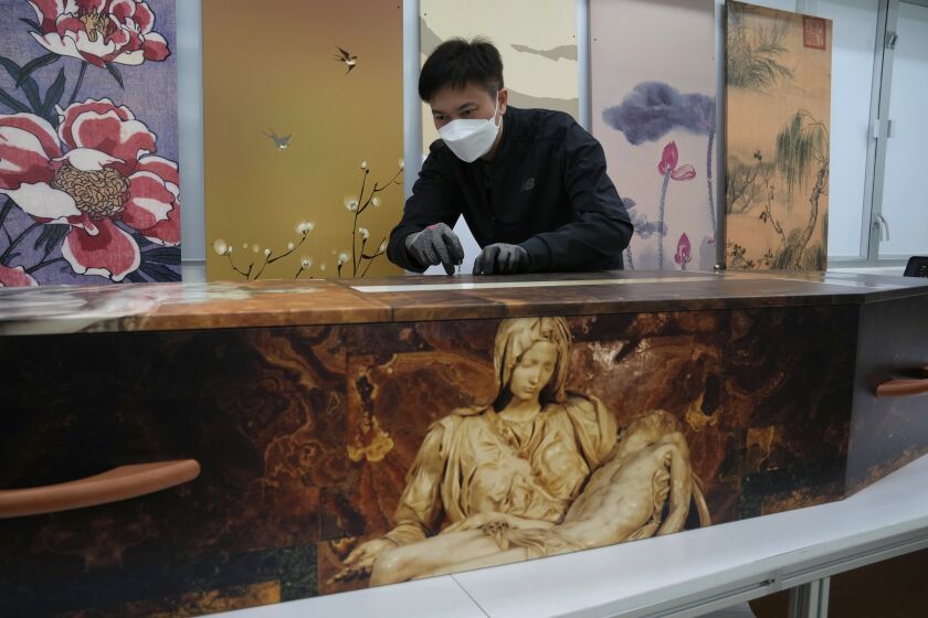 A worker fixes screws on a paper coffin at the Hong Kong factory of LifeArt. 