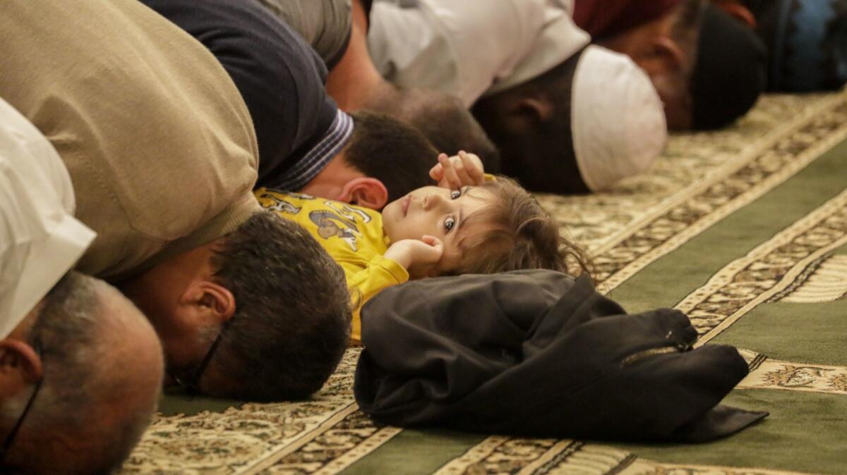 A child plays as men offer their nightly Ramadan prayers this month at Masjid Al-Fatiha.