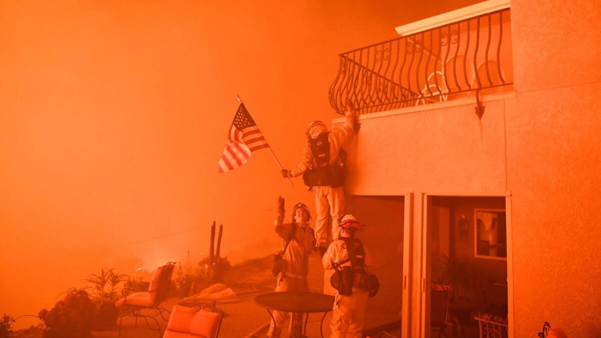 Firefighters save a U.S. flag as flames from the Wall fire close in on a luxury home in Oroville, Calif., on July 8, 2017.