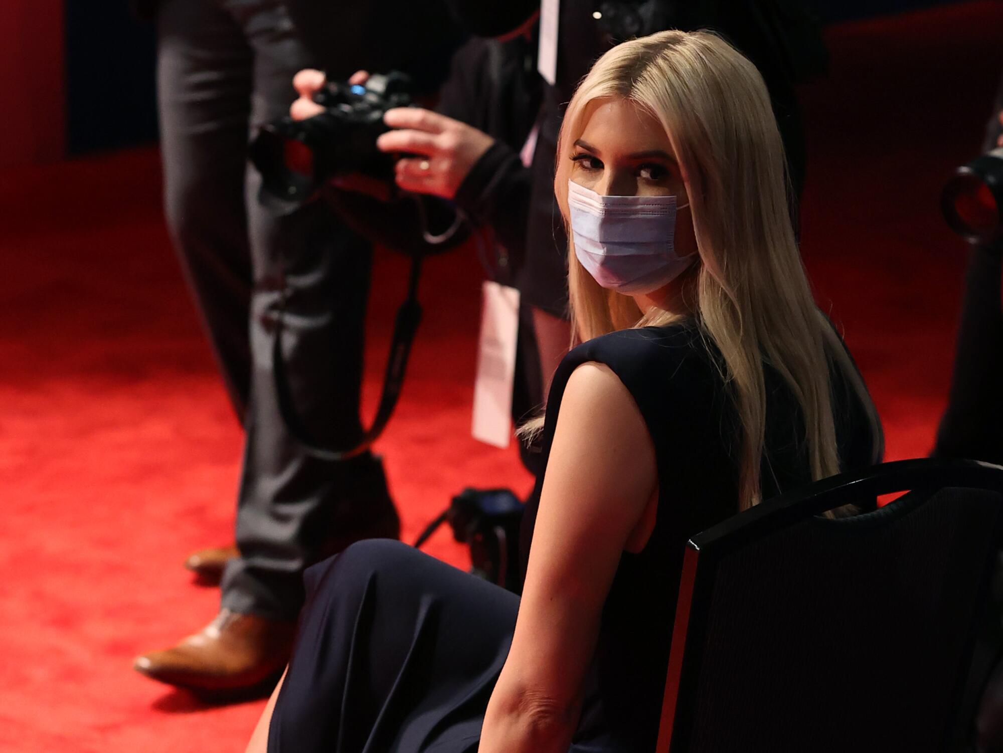 Ivanka Trump wears a mask while sitting in a chair in the debate hall