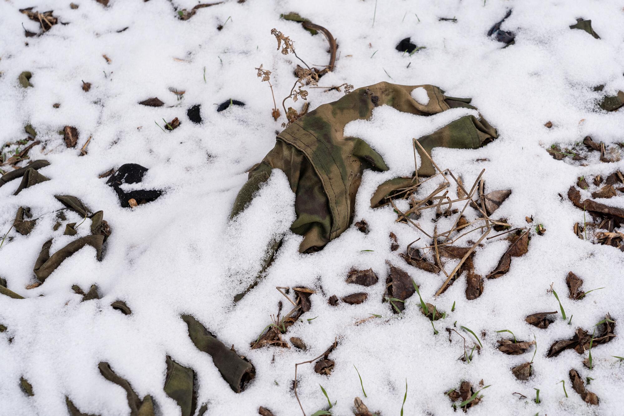 A fragment of Russian fatigues pokes out from under a dusting of snow in a village park in Bilyayivka.