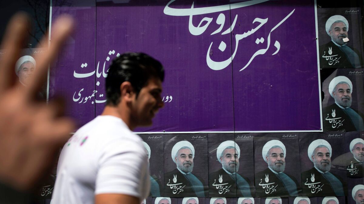 An Iranian man passes portraits of President Hassan Rouhani outside his campaign headquarters in Tehran.