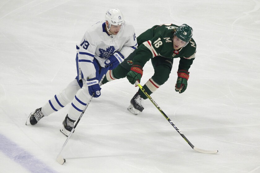 Toronto Maple Leafs center Jason Spezza (19) controls the puck in front of Minnesota Wild center Rem Pitlick (16) during the first period of an NHL hockey game, Saturday, Dec. 4, 2021, in St. Paul, Minn. (AP Photo/Andy Clayton-King)