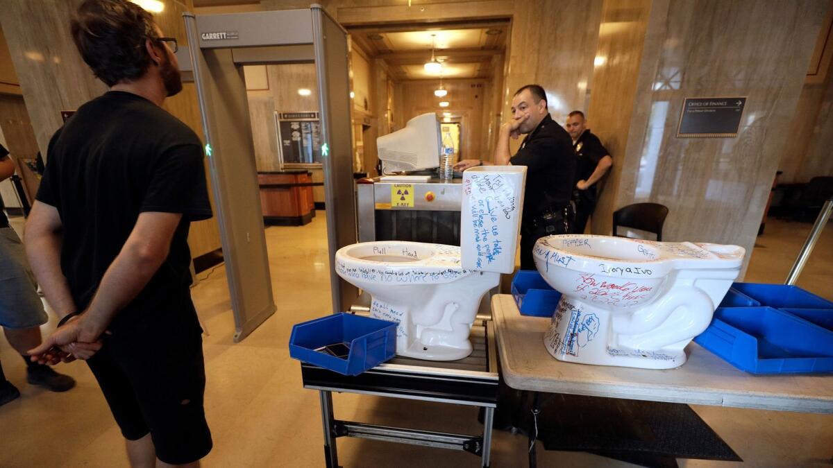A protester waits inside City Hall Wednesday to see if police will let him deliver toilets to Mayor Eric Garcetti to highlight lack of skid row bathroom facilities during the Hepatitis A outbreak.