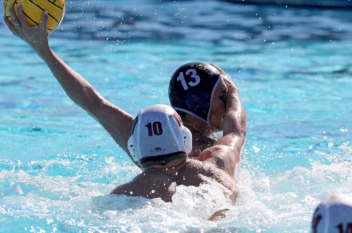 Newport Harbor's Ben Liechty (13) shoots as he is smacked in the face by JSerra's William Schneider (10) on Saturday.