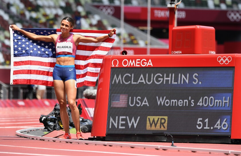Sydney McLaughlin holds a U.S. flag by a screen with her winning 400-meter hurdle time of 51.46 at the Tokyo Olympics.