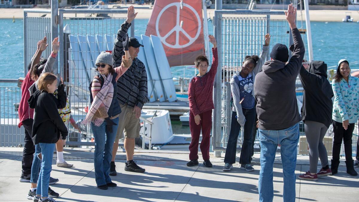 Dave Patterson, a crewman on the Golden Rule, teaches visiting elementary school students the flag semaphore signals for "N" and "D," or "nuclear disarmament," the basis for Gerald Holtom's design for the international peace symbol.