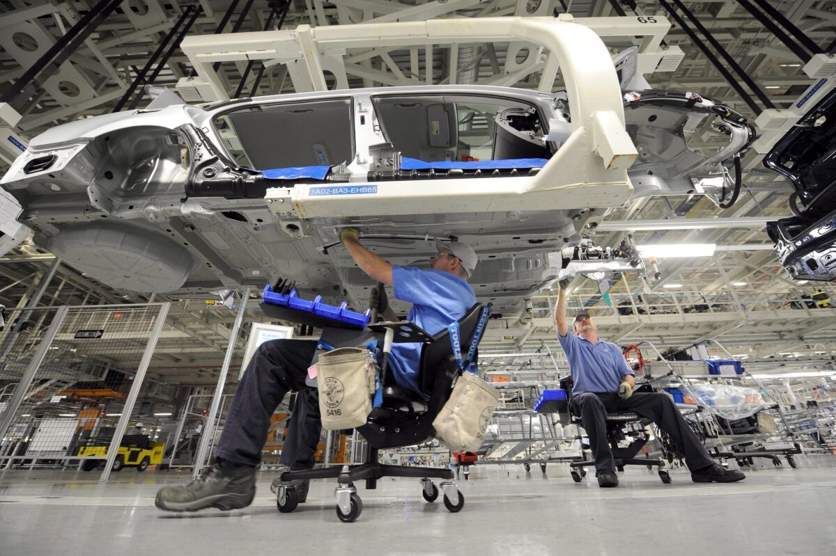 Employees work on the underside of a Passat sedan at the Volkswagen automobile assembly plant in Chattanooga, Tenn.
