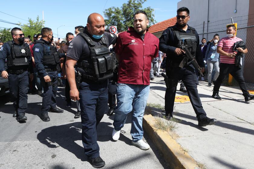 Mexican police detain a factory worker, after they halted their work to protest against the lack of safety measures against the novel coronavirus, COVID-19, outside Electrocomponentes of Mexico, a company in the Mexican city of Ciudad Juarez, Chihuahua State, on the US border, on April 20, 2020. - Thousands of Mexicans are still working in similar "maquiladoras" -- factories set up mainly by US companies to avail of cheap labour -- all along the 3,100-kilometer (2,000-mile) border with the United States. In Juarez alone, among the 160 largest maquiladoras -- which together employ 300,000 workers -- nearly 30 factories deemed non-essential by the government were still operating last Friday, according to Chihuahua Labour Secretary Ana Luisa Herrera. (Photo by HERIKA MARTINEZ / AFP) (Photo by HERIKA MARTINEZ/AFP via Getty Images)