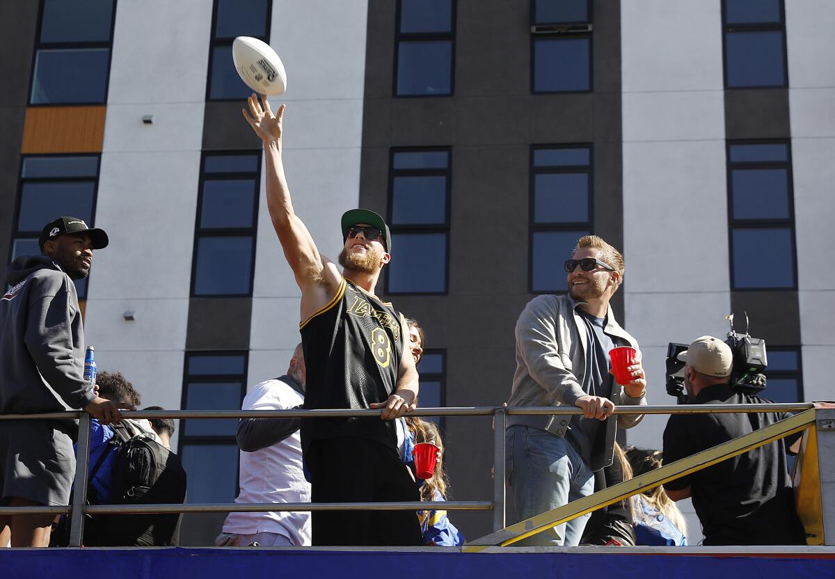 Cooper Kupp, center, throws a football out to the crowd during the Super Bowl parade.