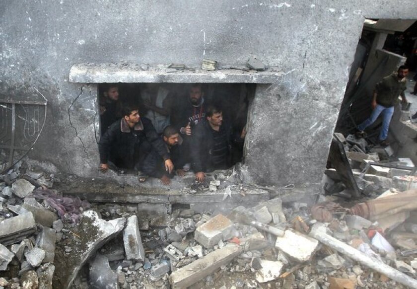 Palestinians search the debris of the Dalu family home following an Israeli airstrike in Gaza City on Sunday that killed at least 12 people, 10 of them members of the family.