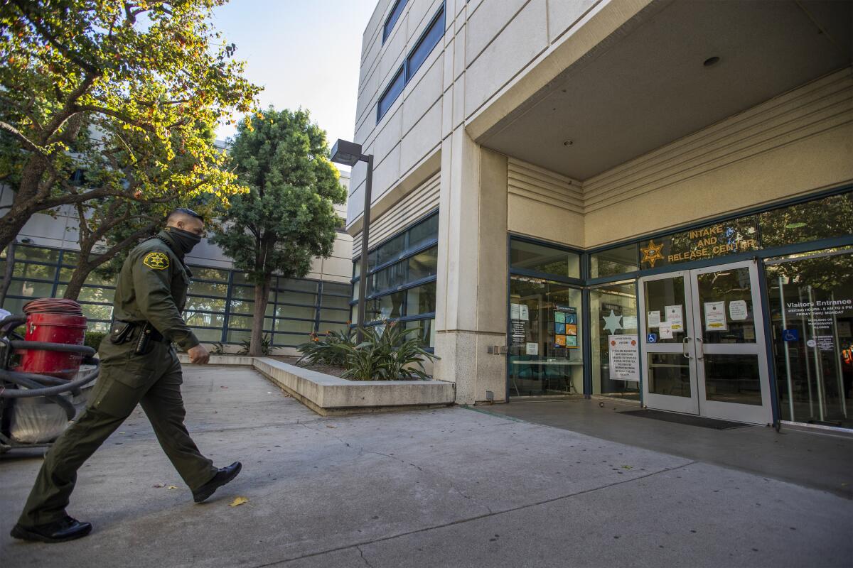 An officer walking toward a building entry marked with a sheriff's department logo and the words "Intake and Release Center"