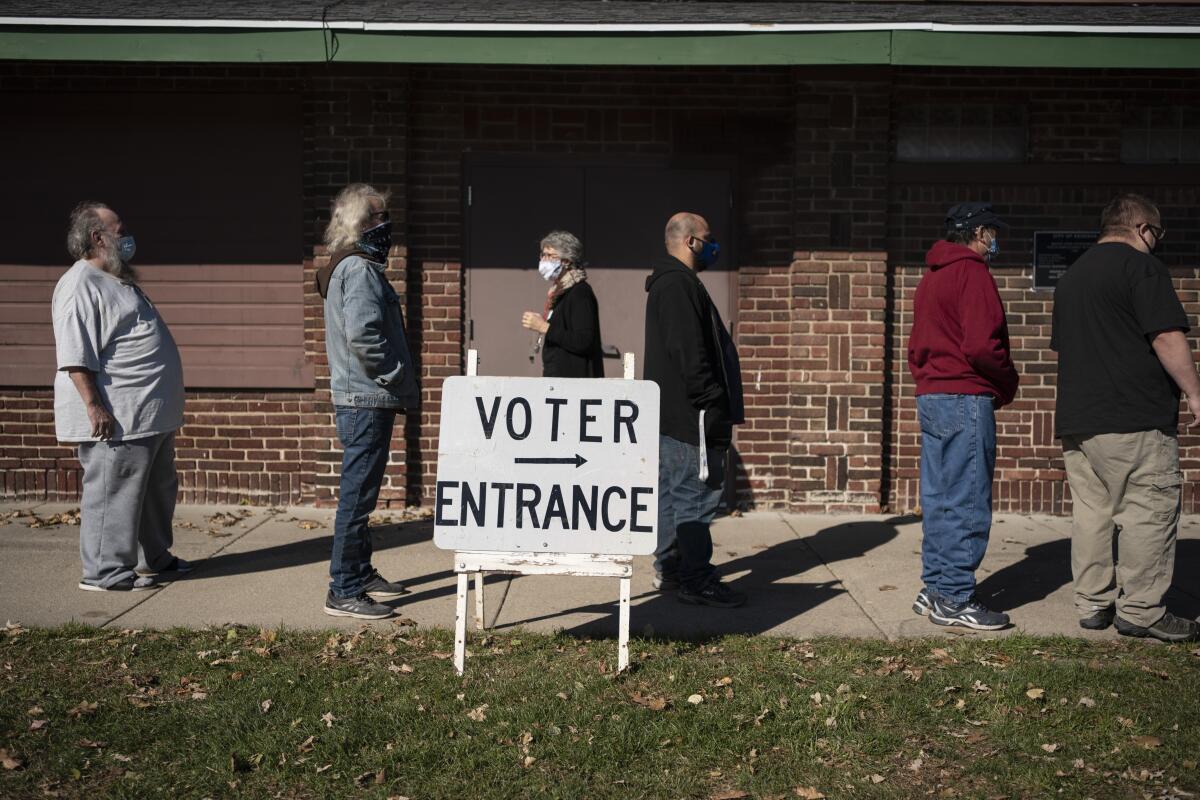 People stand in line near a sign that says "Voter Entrance" with an arrow
