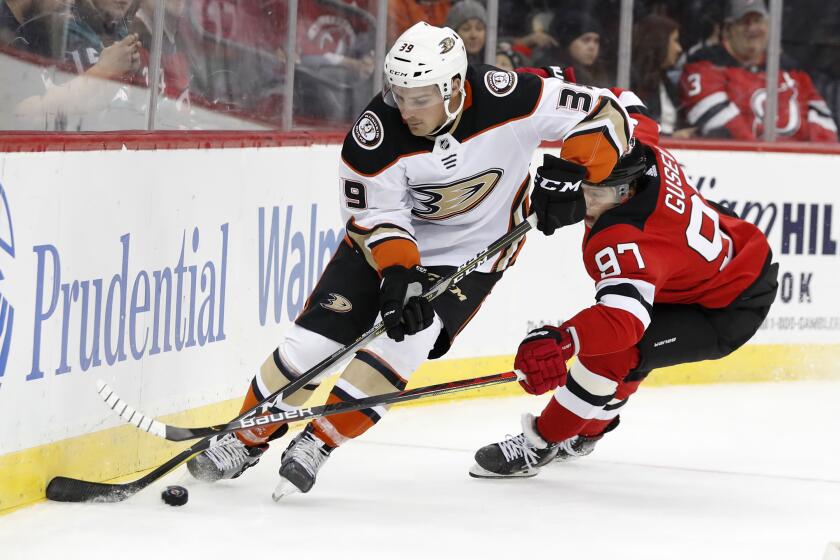 Anaheim Ducks center Sam Carrick (39) keeps the puck from New Jersey Devils left wing Nikita Gusev (97) during the second period of an NHL hockey game Wednesday, Dec. 18, 2019, in Newark, N.J. (AP Photo/Kathy Willens)