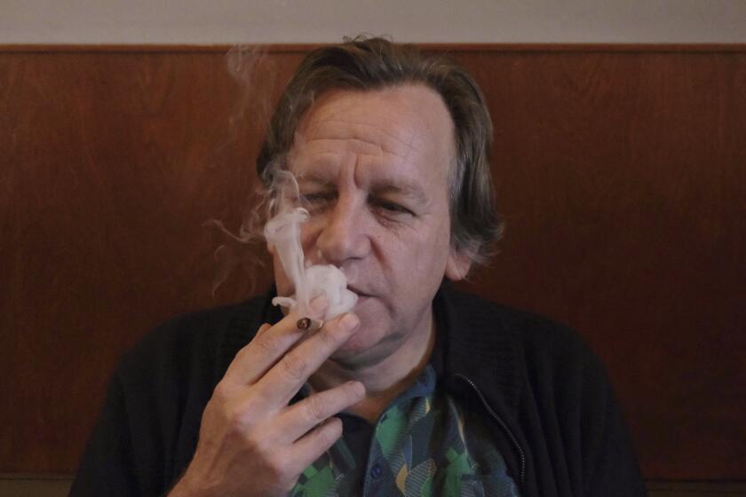Derrick Bergman, presidente de la Unión Por la Abolición de la Prohibición del Cannabis, fuma un cigarrillo de marihuana en el café De Baron en Breda, Holanda, viernes 15 de diciembre de 2023. La hierba cultivada legalmente salió a la venta en dos ciudades holandesas. (AP Foto/Mike Corder)