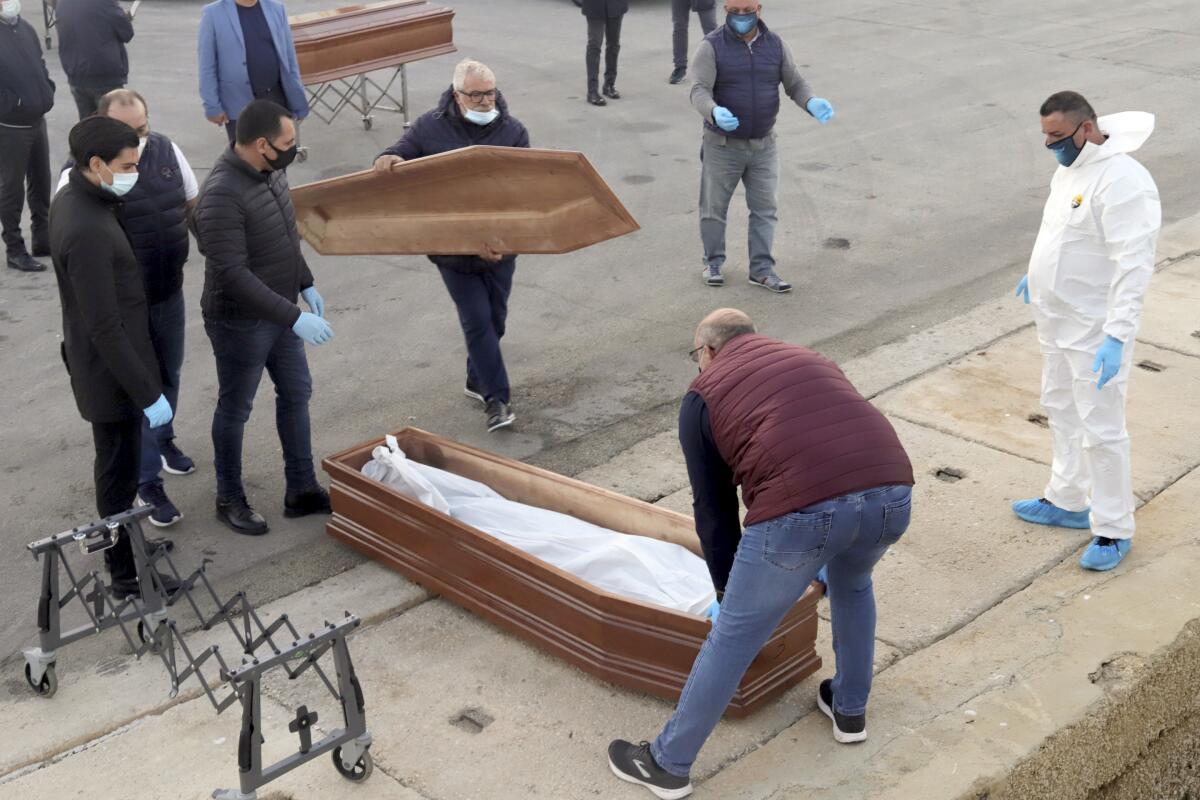 Workers secure a coffin holding the body of a migrant who died at sea.